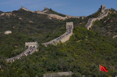 aerial view of a verdant hillside with lots of people walking along the Great Wall of China