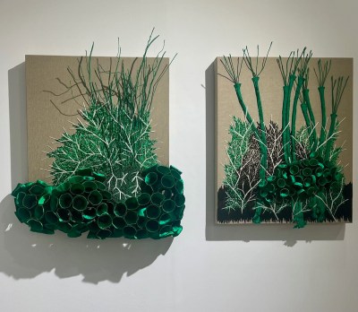 Two paintings showing green flora that appears to come out of the canvas.