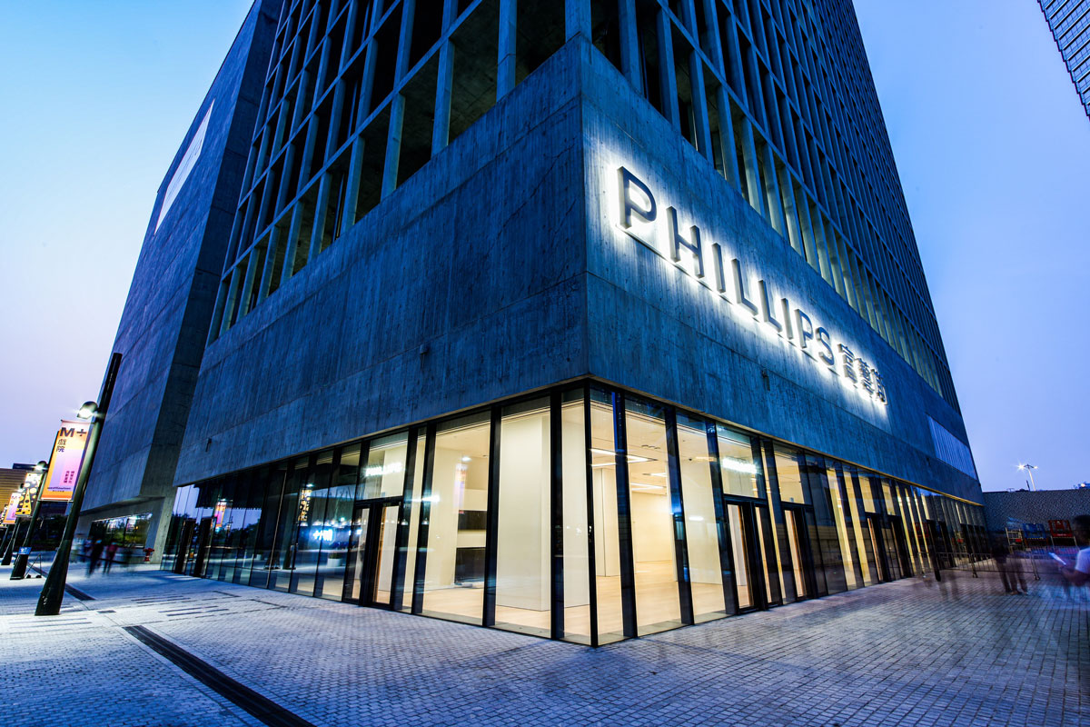 View of the lower levels a concrete high-rise with a glass ground floor that reads Phillips in English and Chinese on its facade.