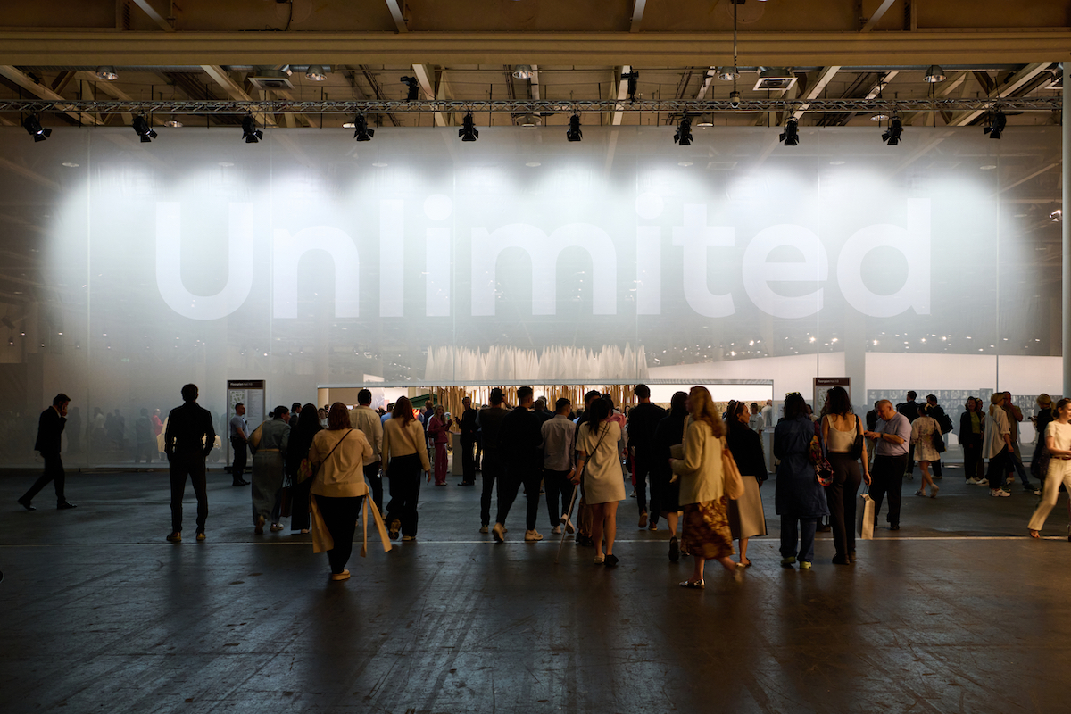 A crowd of people beneath a large sign that reads 'Unlimited.'