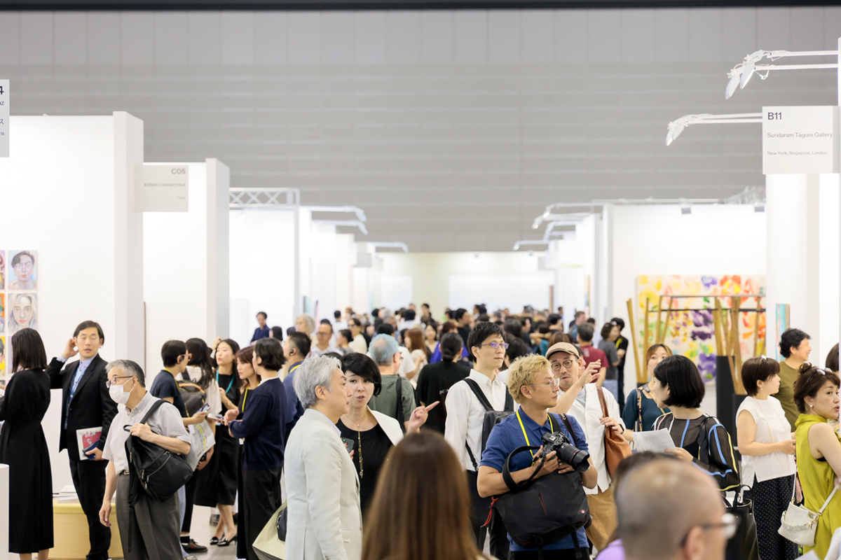 Crowds of people mill about the aisles of an art fair in Tokyo.