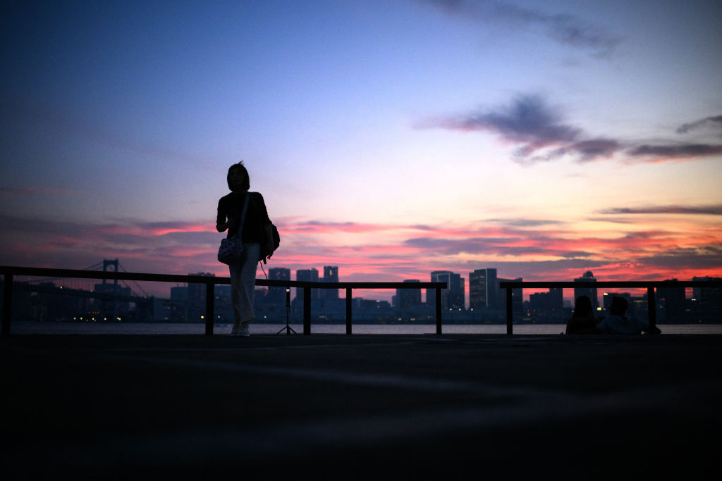 People are silhouetted during dusk as they visit the Toyosu Gururi park in Tokyo's Koto district on July 3, 2024. (Photo by Philip FONG / AFP) (Photo by PHILIP FONG/AFP via Getty Images)