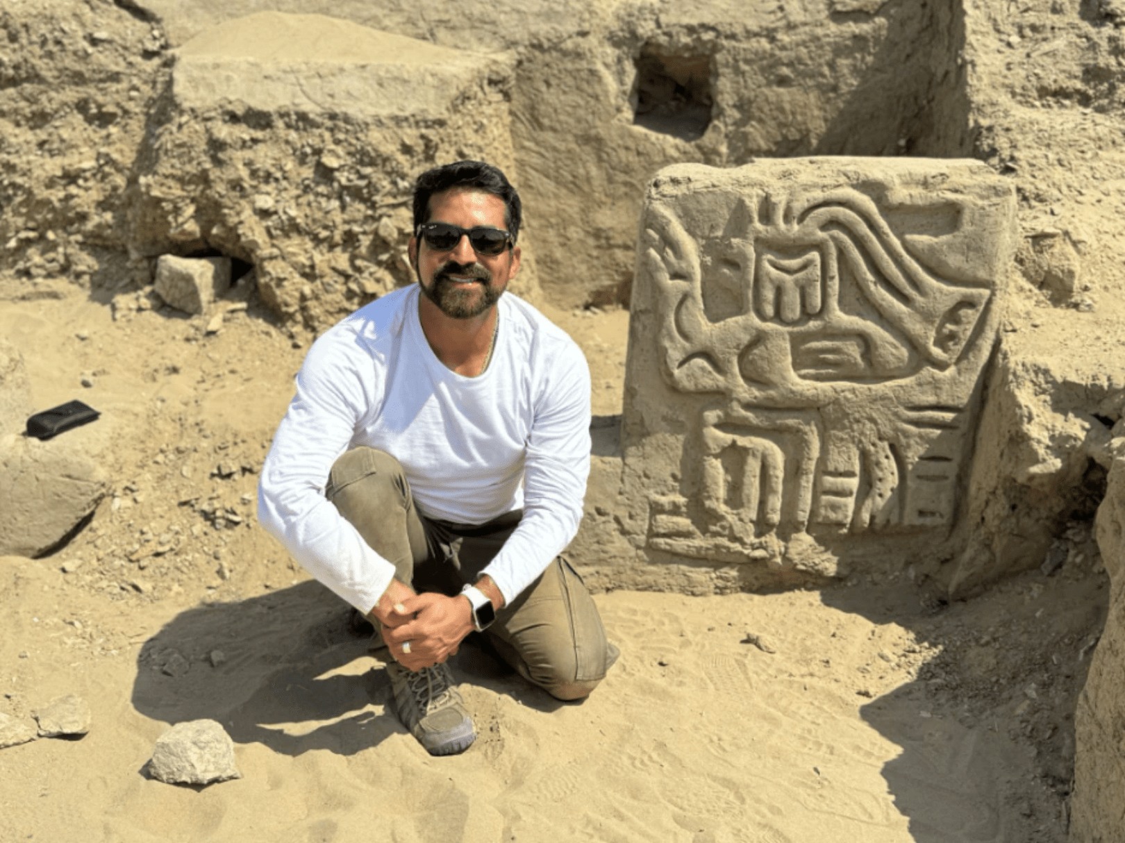 Field Museum scientist Luis Muro Ynoñán with the carving of a mythological bird creature in La Otra Banda, Cerro Las Animas.